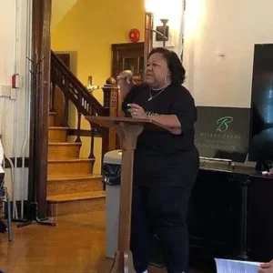 Bulinda stands at a podium giving a talk