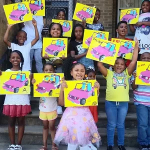 group of children holding up their paintings of a car
