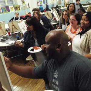 Chet demonstrating how to paint to a group of people