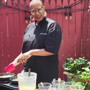 person wearing glasses and holding red spatula smiling